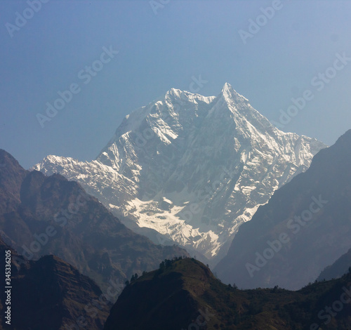 A hazy view of the Nilgiri South peak rising above the hills as seen from the village of Tatopani on the Annapurna Circuit trekking trail in Nepal.