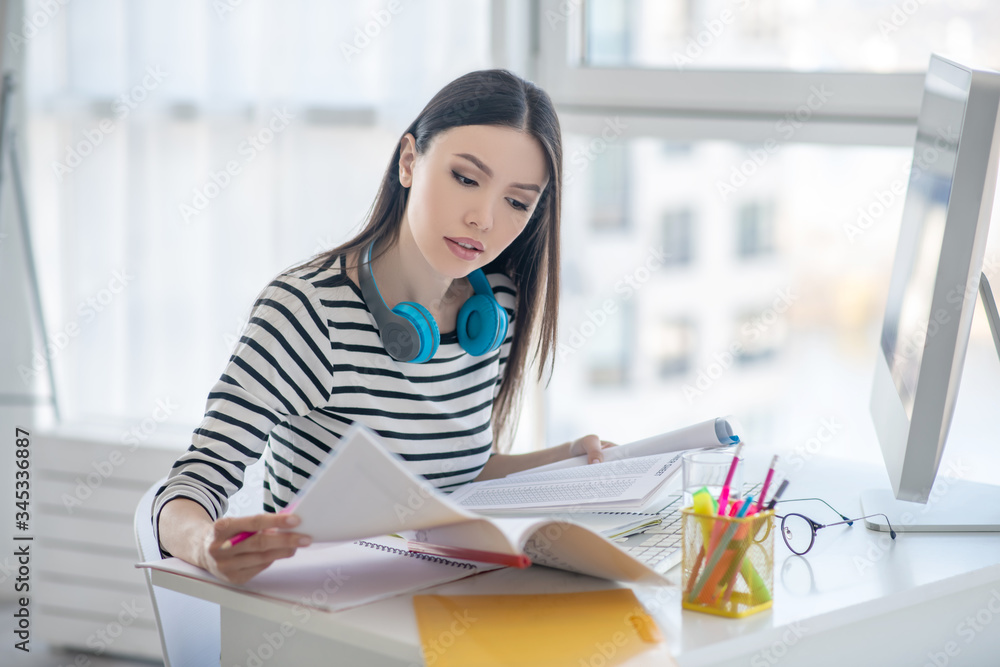Pretty brunette woman working with papers and looking interested Pretty brunette woman working with papers and looking interested