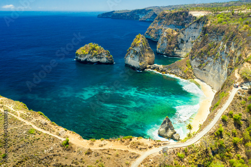 Traveler hiker standing on the top of mountain cliff and enjoy amazing nature landscape with scenery tropical beach and clear sea water. Bali  Indonesia. Aerial view.