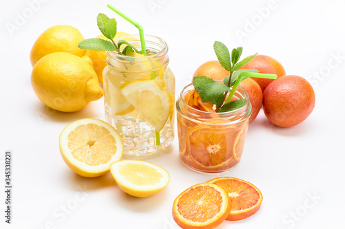 Pitcher and glass of homemade lemonade and orangeade with some mint leaves