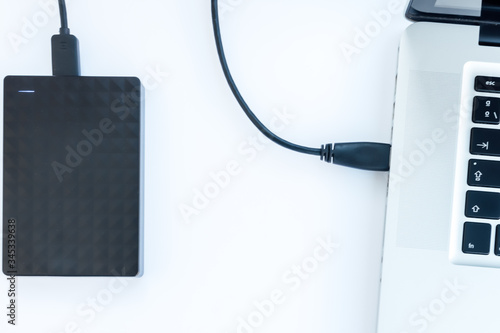 black ssd hard drive with cable connected to a laptop with white background photo