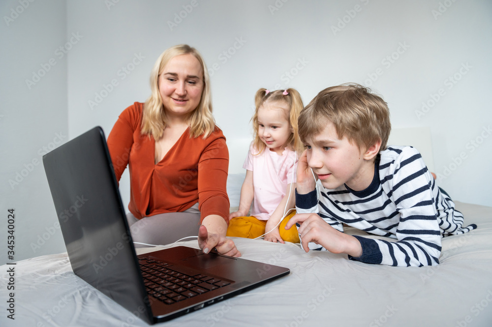 Girl and boy using laptop amd earphones at home whith mom