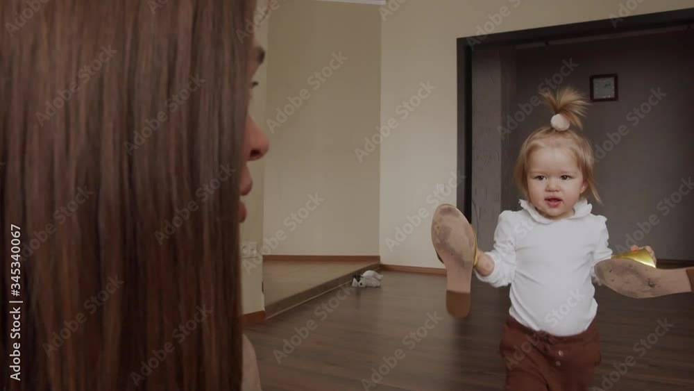 Charming baby girl walking to her mother and taking off mother shoes. Funny game at home. Charming baby girl walking to her mother and taking off mother shoes. Funny game at home.