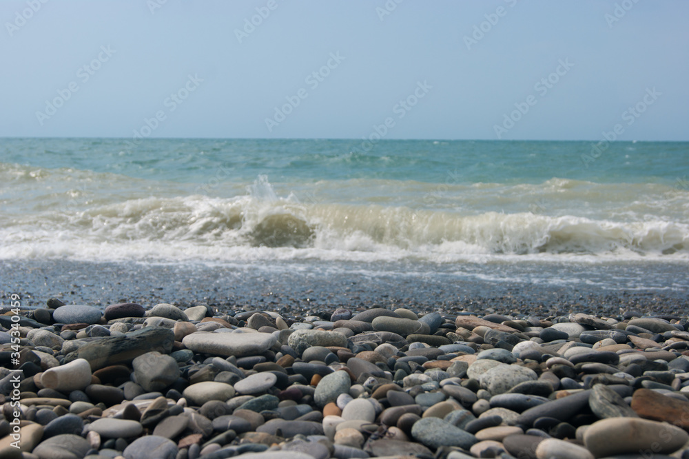 A small storm three or four points at sea, the wave hits the shore with a large pebble.