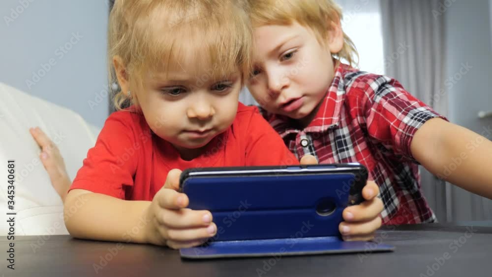 children watch online video on a smartphone. little boy and girl brother sister watch lifestyle online streaming broadcasting cartoons on the phone children watch online video on a smartphone. little boy and girl brother sister watch lifestyle online streaming broadcasting cartoons on the phone