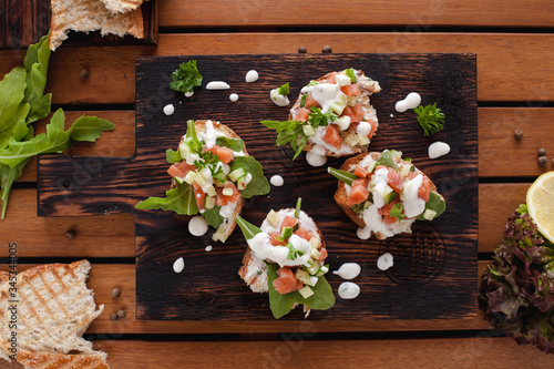 Tasty bruschetta with salmon on wooden board