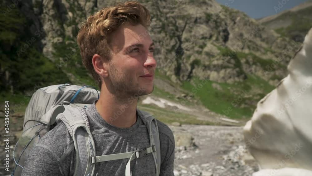 Young man in hiking outfit laughing and enjoying the beautiful mountain landscape, slow motion Young man in hiking outfit laughing and enjoying the beautiful mountain landscape, slow motion
