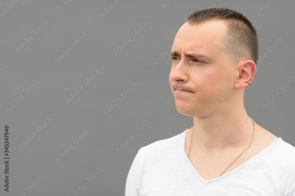 Face of handsome man thinking against gray wall outdoors Face of handsome man thinking against gray wall outdoors