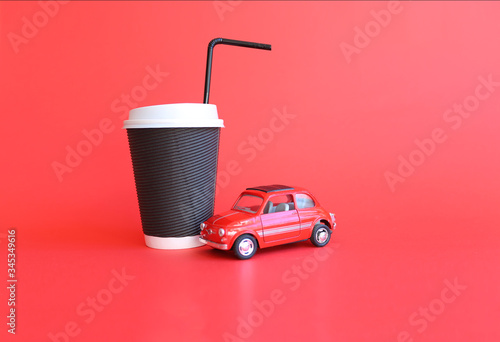 Design concept of mockup coffee cup and little red toy car isolated on red background. Copy space for text photo