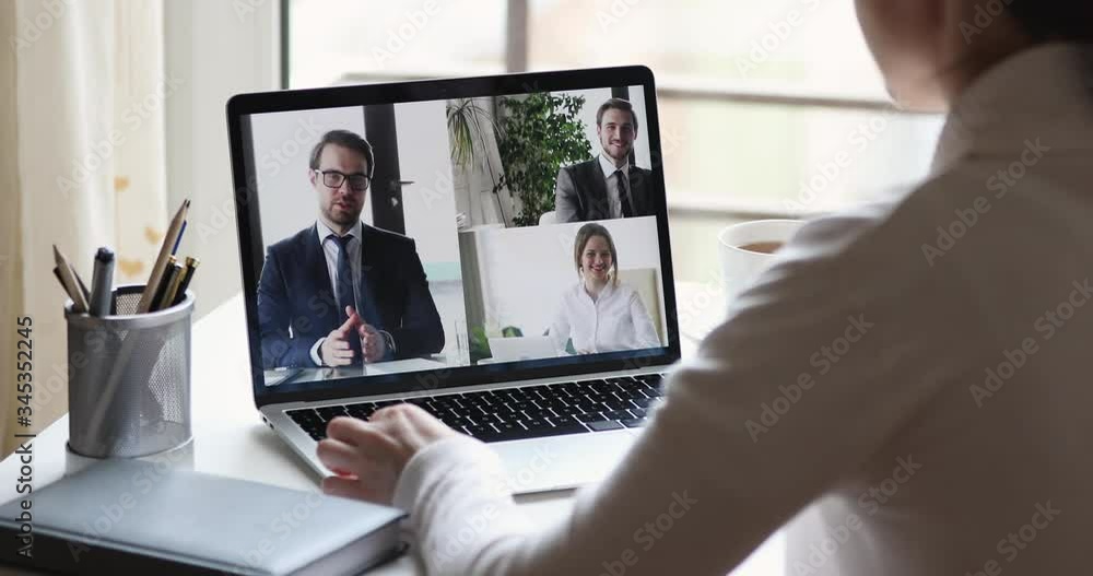 Over shoulder closeup view of business woman videoconferencing partners team by online video call virtual app. Remote worker conferencing colleagues group on pc laptop screen working from home office. Over shoulder closeup view of business woman videoconferencing partners team by online video call virtual app. Remote worker conferencing colleagues group on pc laptop screen working from home office.