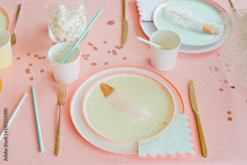 Decorative table setting in pastel colors with pink tablecloth, paper colorful dishes, cups, golden cutlery. birthday for girl, baby shower or hen party decoration. photo