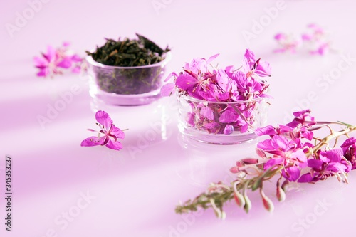 Beautiful composition of willow-herb tea and fresh flowers on pink background