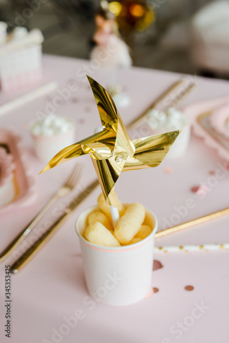 Golden pinwheel in paper cup on decorative party table for girl birthday. Close up