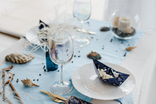 Party table setting in sea style. Elegant plates, glasses, in blu? colors. Paper boats with marshmallow. Birthday or baby shower boy concept.