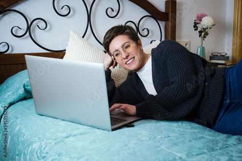 Woman lying in bed with a laptop computer telecommuting
 photo