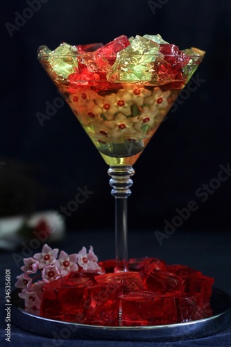 Sweet jelly dessert, design food, creative meals with vanilla flowers in dark mood on black background