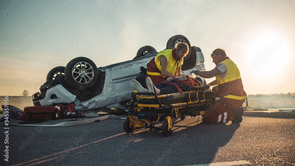 On the Car Crash Traffic Accident Scene Paramedics Saving Life of a Female Victim who is Lying
