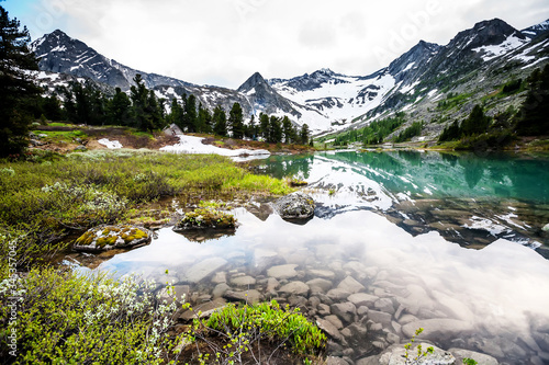 Green lake between mountains in cloudy day