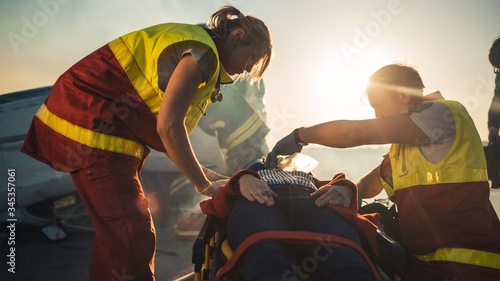 Foto On the Car Crash Traffic Accident Scene: Paramedics Saving Life of a Female Victim who is Lying on Stretchers