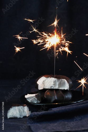 Obraz na płótnie Chocolate marshmallows with sparklers, design food, dark mood on black background w salonie
