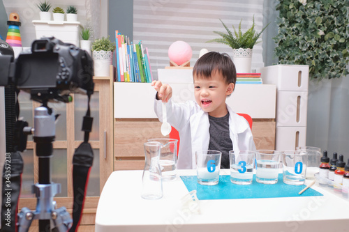 Asian school boy making easy chemistry experiments and recording a video for his followers, Young blogger kid posing in front of camera for vlog, Children make vlog for social media channel concept