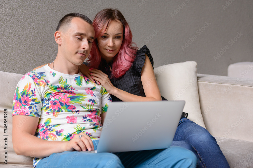 Portrait of couple using laptop together in the living room at home