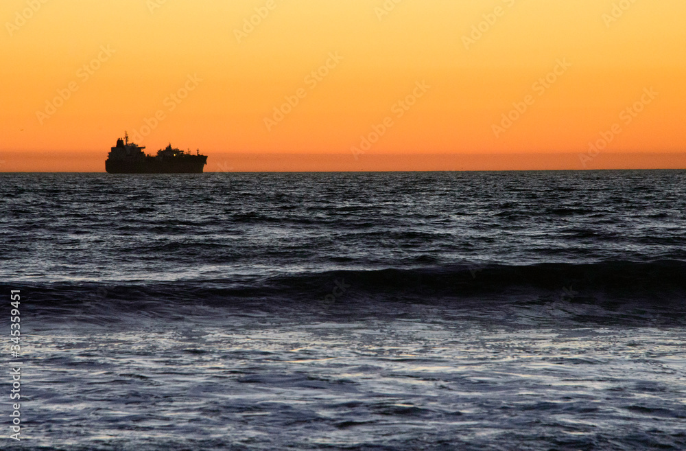 sunset over the sea with a ship silhouette and waves in Sunset beach near Long beach, California sunset over the sea with a ship silhouette and waves in Sunset beach near Long beach, California