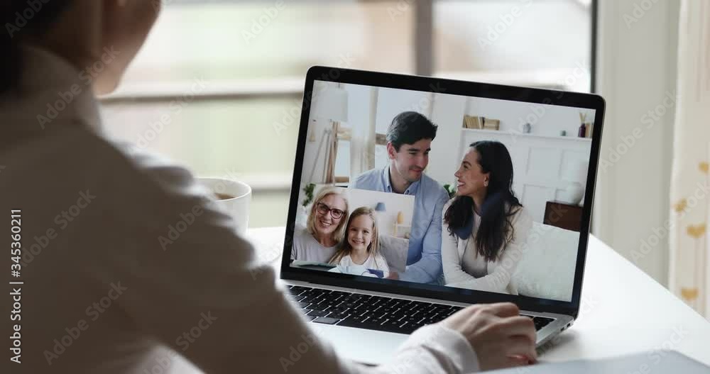Young woman waving hand video calling long distance relatives by web cam. Happy big family chatting in conference group chat during social quarantine concept. Over shoulder closeup laptop screen view Young woman waving hand video calling long distance relatives by web cam. Happy big family chatting in conference group chat during social quarantine concept. Over shoulder closeup laptop screen view