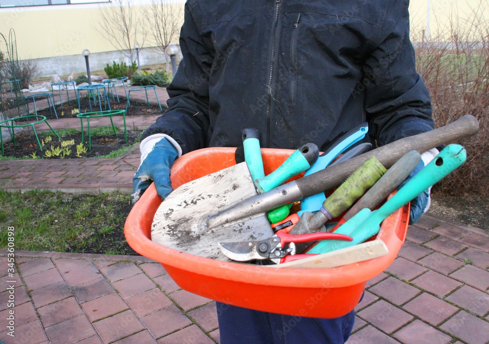 Woman in blue sport suit holding different garden tools. Garden concept Woman in blue sport suit holding different garden tools. Garden concept
