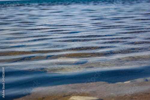 The surface is salty sea water, swaying in small waves near the shore, through the transparent bottom you can see stones and pebbles 