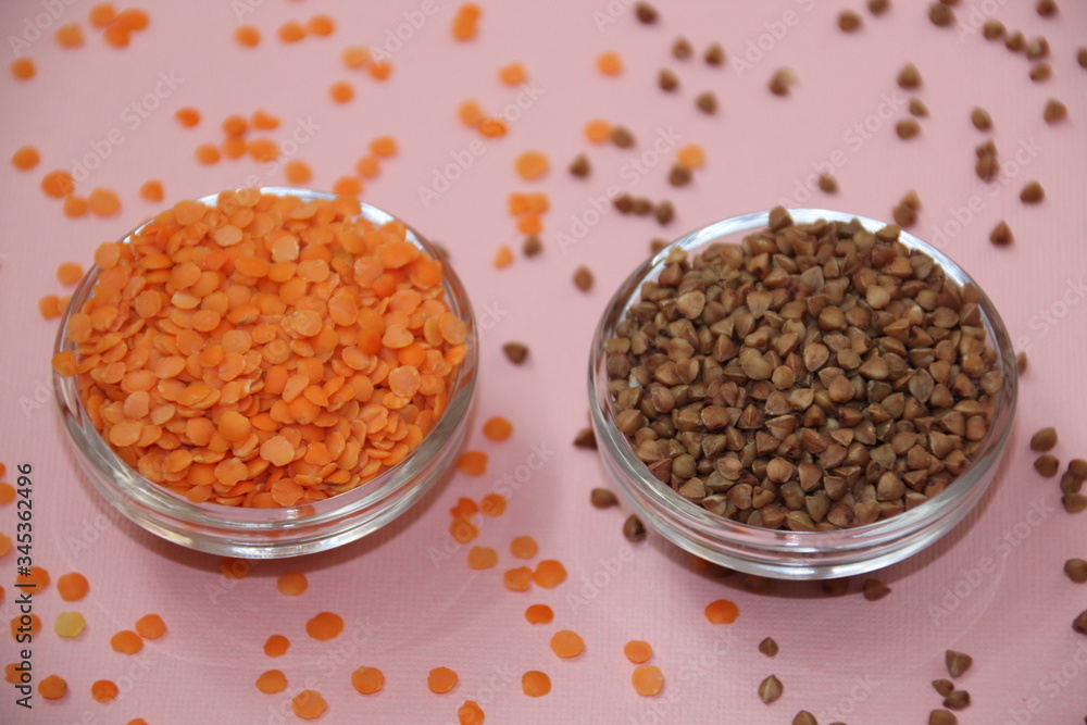 red lentils and buckwheat in transparent bowls on a pink background. red lentils and buckwheat in transparent bowls on a pink background.