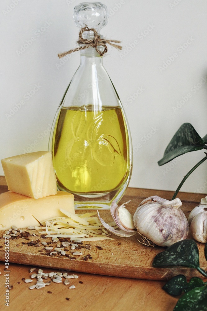 Art composition, design food - oil, garlic, spices and cheese on wooden table and white background