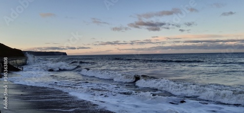 Sandy beach view with waves at sunset in Whitby  North Yorkshire