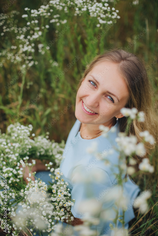 beautiful blonde girl in a field of daisies. wreath of wildflowers on his head. woman in a blue dress in a field of white flowers. charming girl with a bouquet of daisies. summer tender photo beautiful blonde girl in a field of daisies. wreath of wildflowers on his head. woman in a blue dress in a field of white flowers. charming girl with a bouquet of daisies. summer tender photo