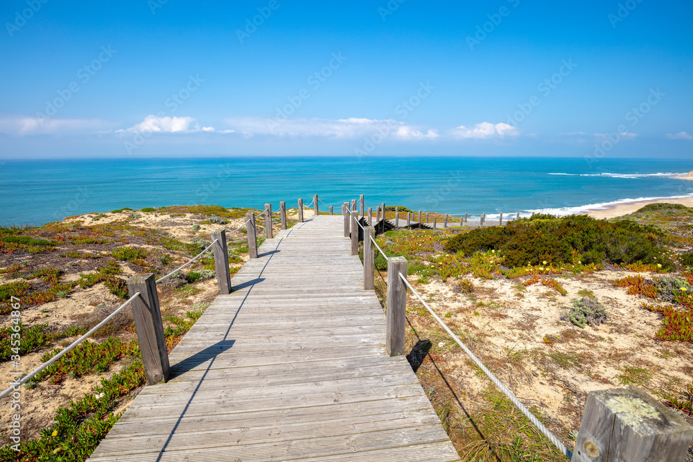 Paredes Panoramic Boardwalk. The wooden stairway on the rocky seashore on a sunny day. Polvoeira the beach, Portugal
