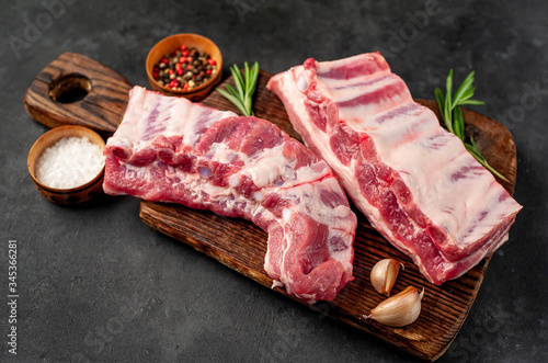 raw pork ribs with spices on a cutting board on a stone background photo