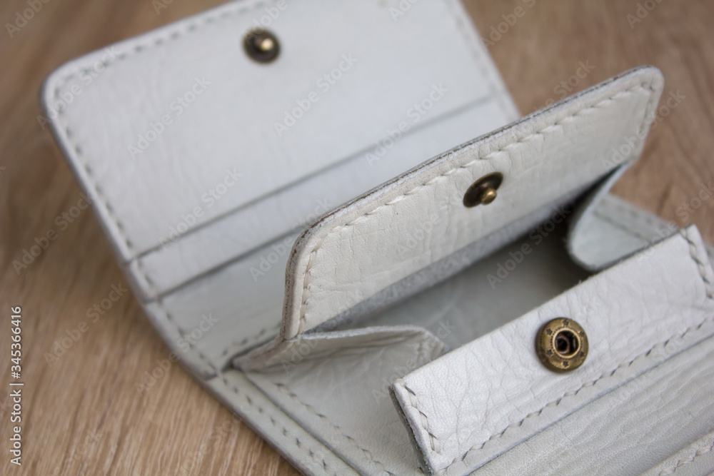 details close up of a white handmade leather wallet on a light wooden table details close up of a white handmade leather wallet on a light wooden table