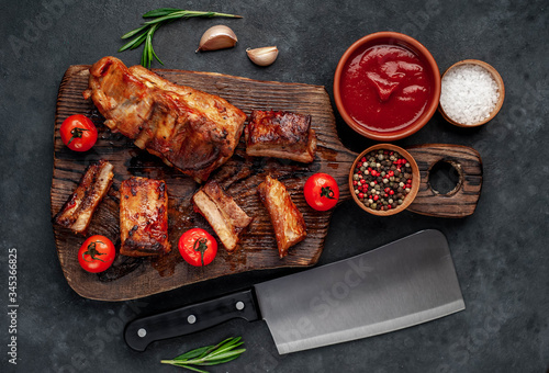 Grilled pork ribs with spices on a cutting board on a stone background