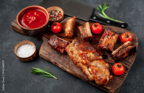 Grilled pork ribs with spices on a cutting board on a stone background