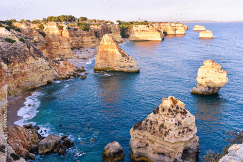 Viewpoint of the natural arches, orange cliffs and turquoise waters, at sunset. Concept of tourism and travel. Algarve, Portugal
