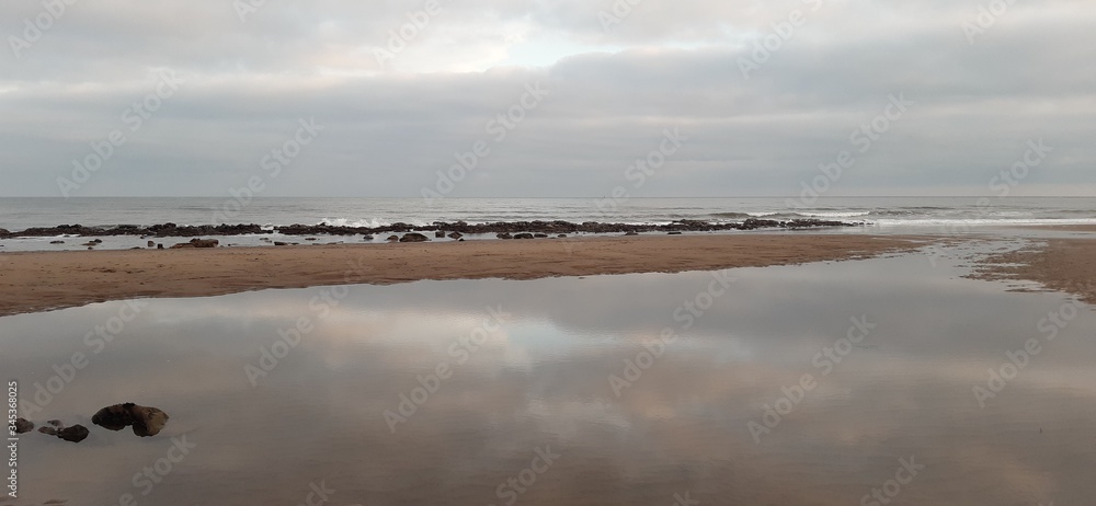 View over Whitby beach with rocks, reflections and pools