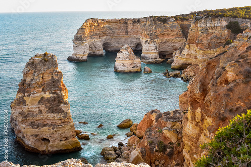 View from above from the viewpoint of the natural arches. . Orange cliffs and turquoise waters. Concept of tourism and travel. Algarve  Portugal