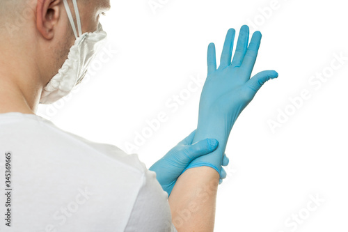 Young surgeon doctor in latex protective gloves in white protection mask on white background. Man in medical gloves and on protective face mask. Coronavirus COVID-19 protection.