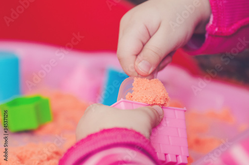 The hands of a child playing with kinetic sand