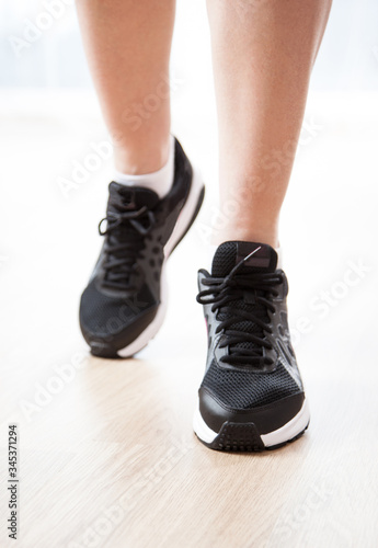 Female legs wearing in black sneakers