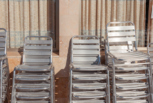 Metal chairs stacked next to outdoor tables © Nemesio