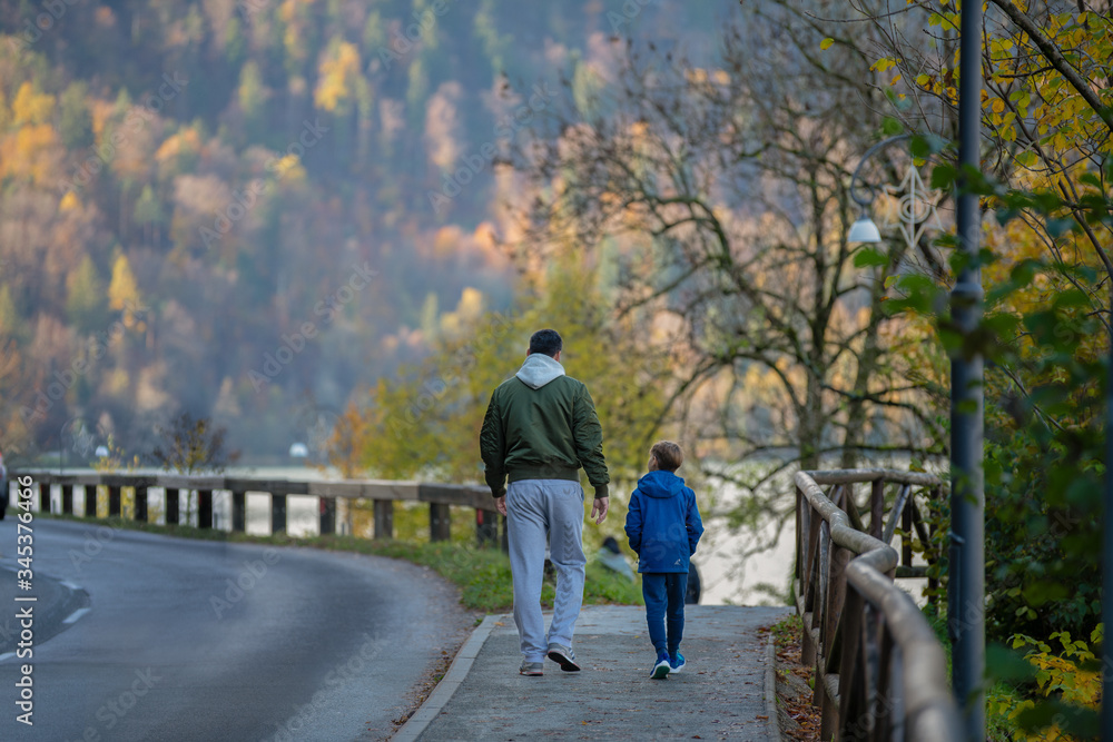 Father and son enjoy in walk by the road near forest in autumn Father and son enjoy in walk by the road near forest in autumn