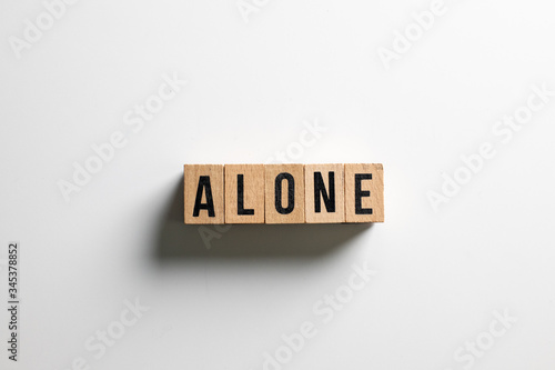 " alone " text made of wooden cube on White background.