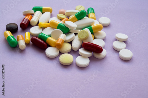 Colorful pills and capsules on a purple background, macroshot tablets 