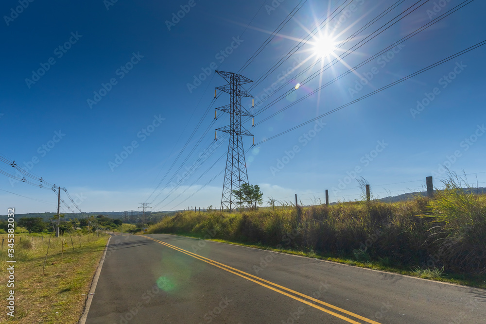 power transmission towers next to the road with blue sky in the background